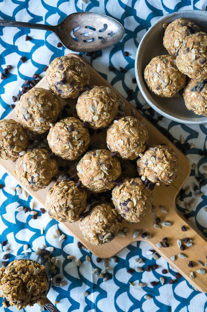 energy balls with sunflower seeds on a wooden cutting board on a white and blue background