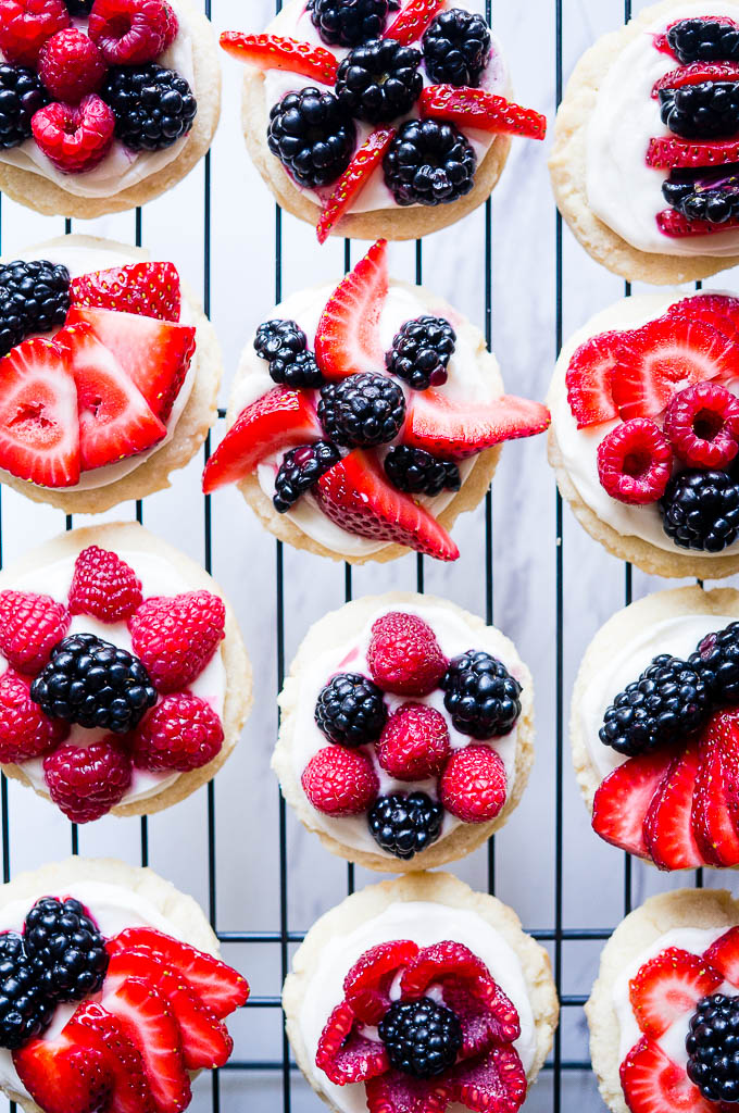 Patriotic Mini Fruit Pizzas.  A fun dessert for 4th of July with a classic sugar cookie base, a scrumptious cream cheese frosting, and your choice of red and blue fruit!