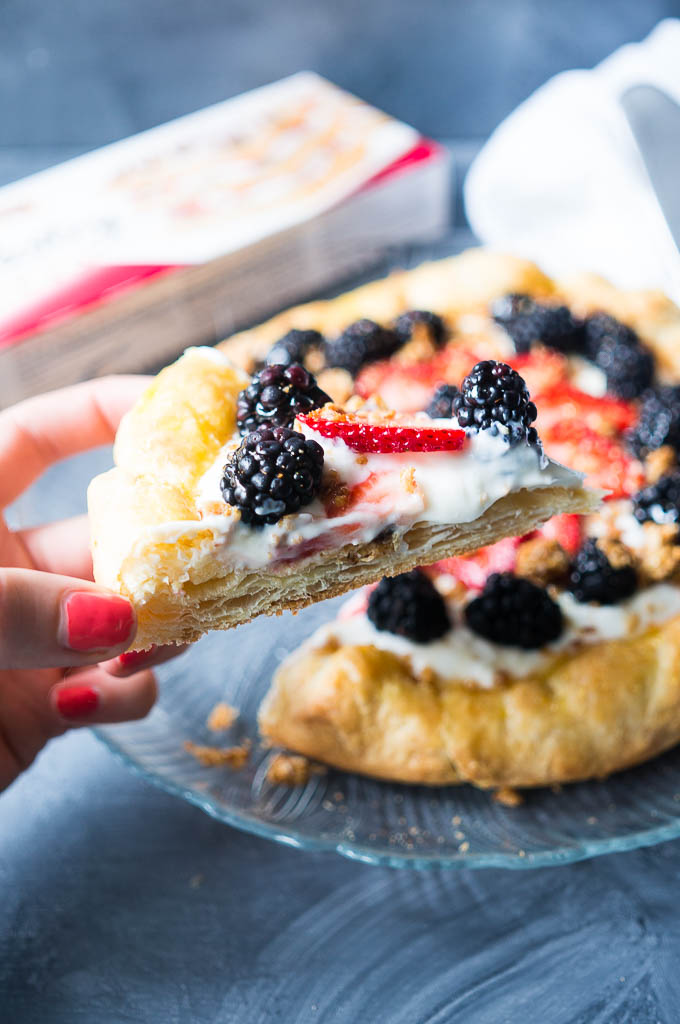 Fruity Granola Breakfast Pizza. Only 5 ingredients! Flaky puff pastry layered with luscious greek yogurt, berries, granola, and drizzled with honey. 