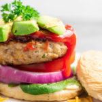 Turkey burgers with toppings on a white background.