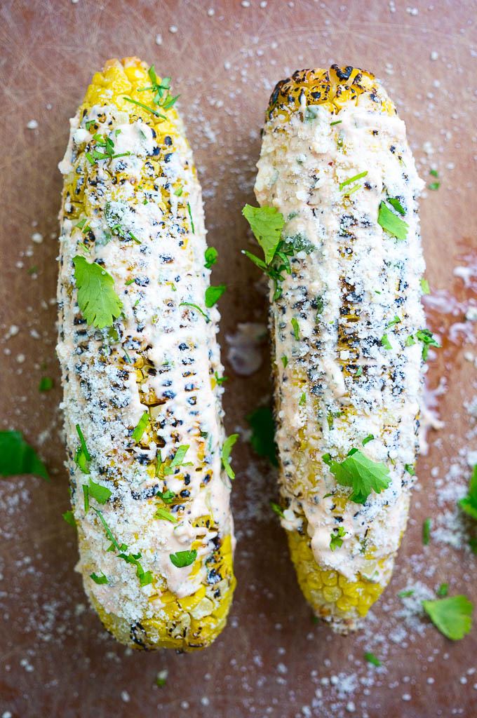 Grilled Mexican Street Corn is lathered in a spicy mayo and sour cream mixture, then sprinkled with cilantro and parmesan cheese.