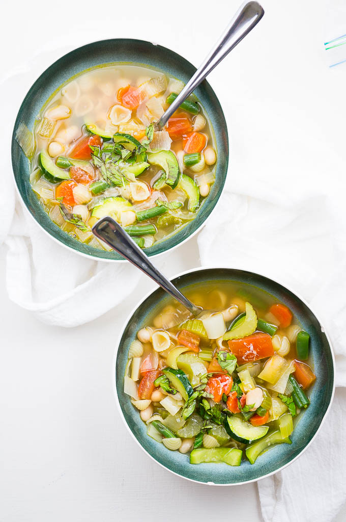 Provençal Summer Vegetable Soup has a light, delicate broth with a simple mix of warm weather produce, small pasta shells, cannellini beans, and fresh ribboned basil.