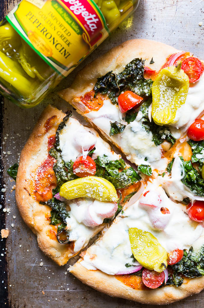 Greek Salad Pizza - everything that you love to eat in a classic greek salad, but piled high on a cheesy pizza with fresh mozza, oregano rubbed kale, and crisp peperoncini's.