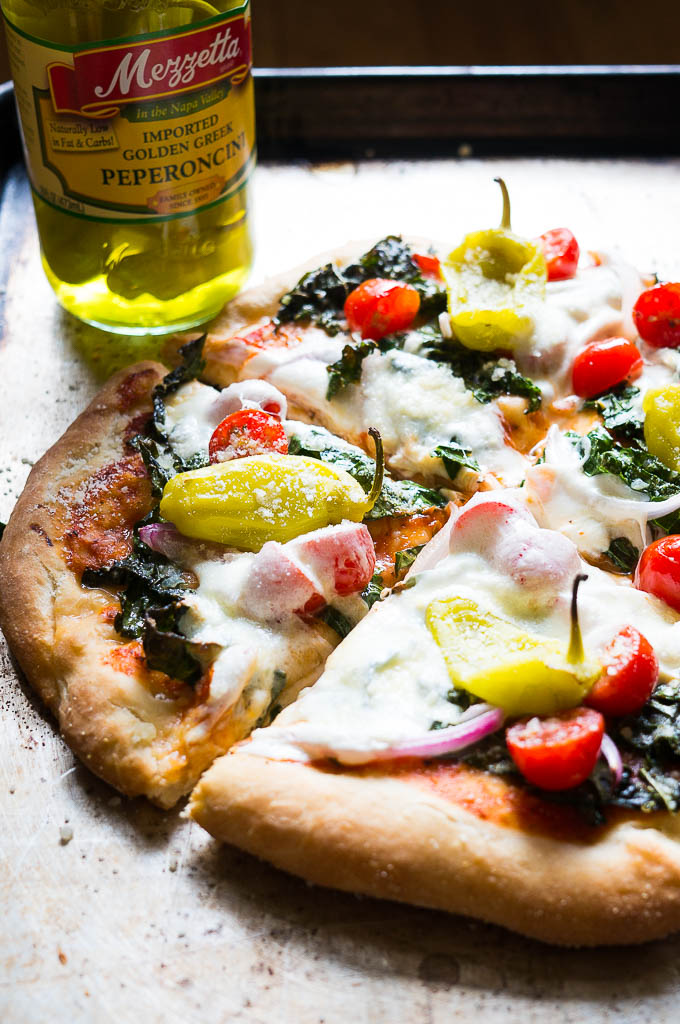 Greek Salad Pizza - everything that you love to eat in a classic greek salad, but piled high on a cheesy pizza with fresh mozza, oregano rubbed kale, and crisp peperoncini's.