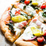 Greek Salad Pizza - every that you love to eat in a classic greek salad, but piled high on a cheesy pizza with fresh mozza, oregano rubbed kale, and crisp peperoncini's.