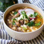 Pressure Cooker Simple Pork Posole with hearty hominy, chunks of tender pork loin, and a sprinkling of fresh radishes, cilantro, and queso fresco