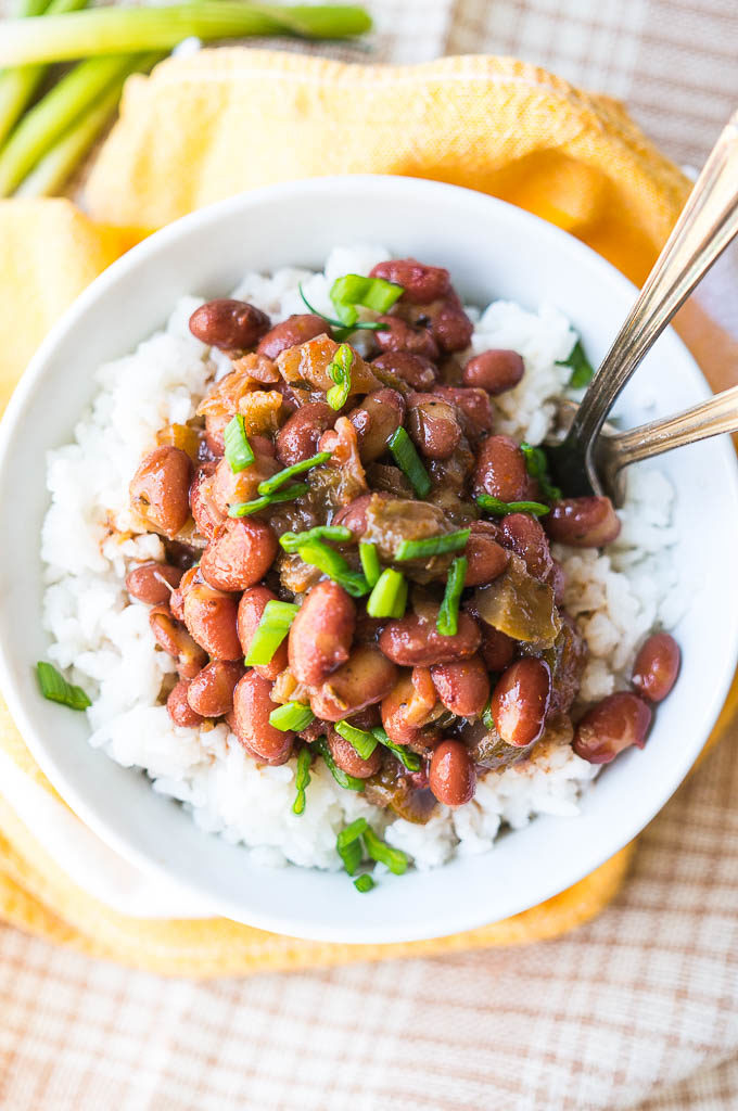 Red beans and white rice in a white bowl on a yellow napkin.