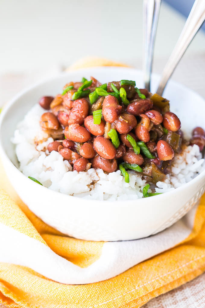 Red beans and white rice in a white bowl on a yellow napkin.