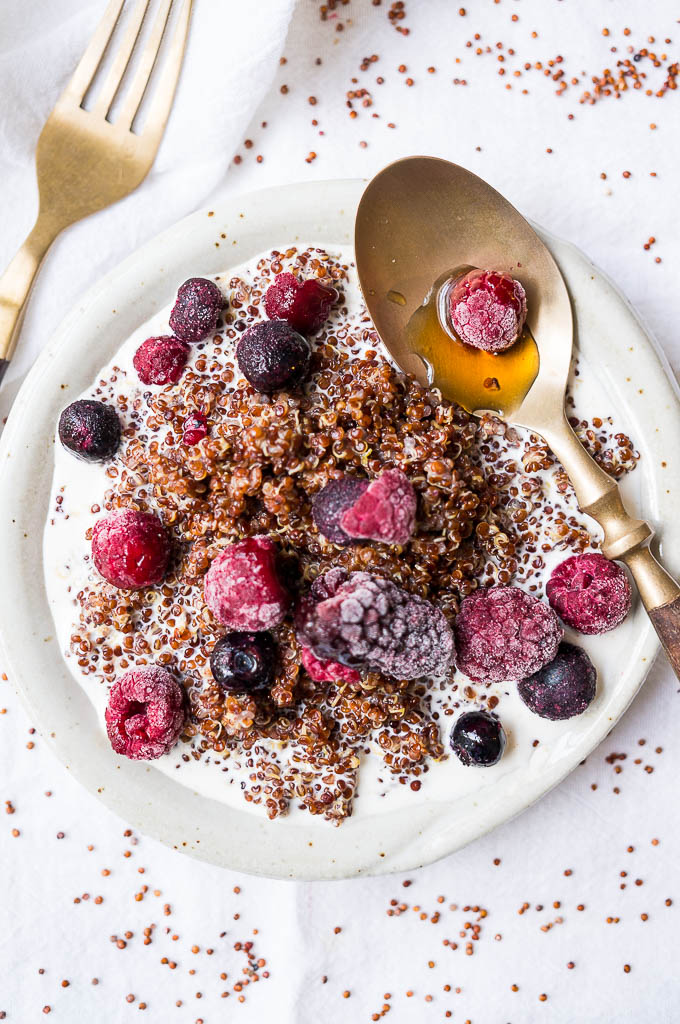 Quinoa and frozen berries on a white plate.