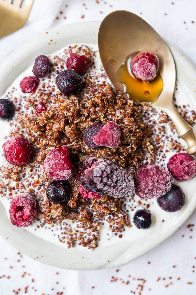 Quinoa and frozen berries on a white plate.