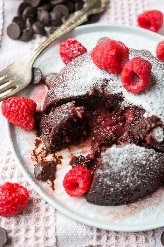 Chocolate Cake with raspberries and chocolate chips on a white plate with pink cloth background.