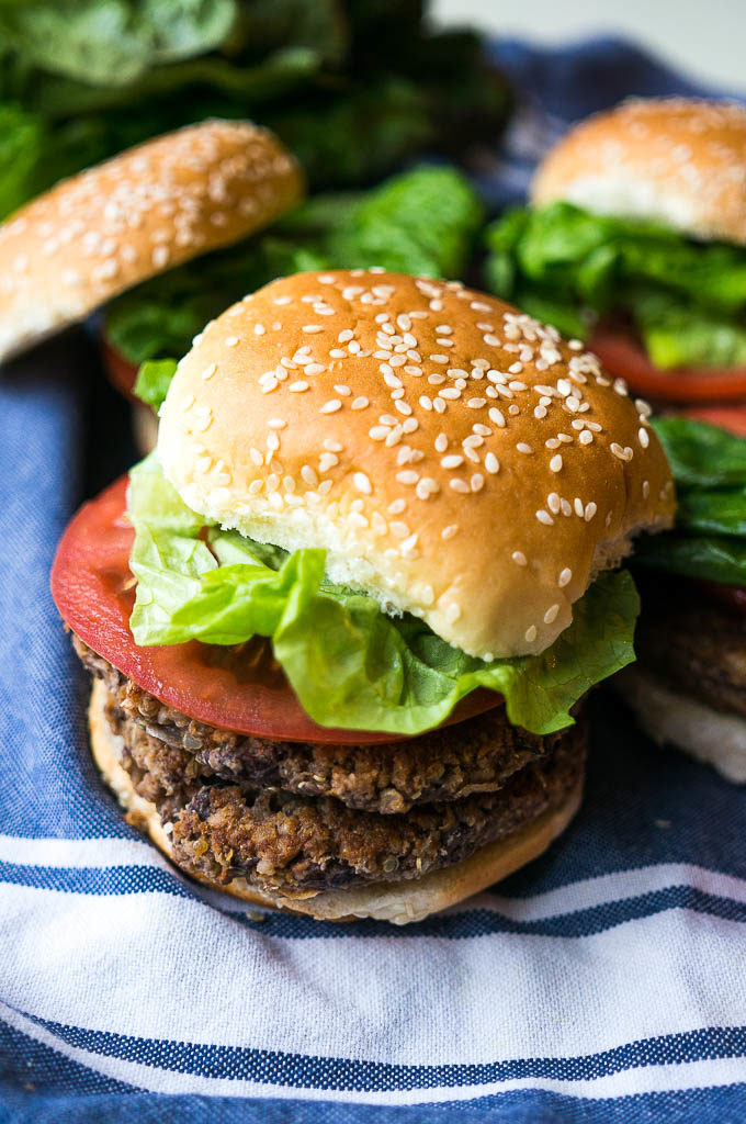 Hamburger with lettuce, tomato, and bun on a blue and white napkin.