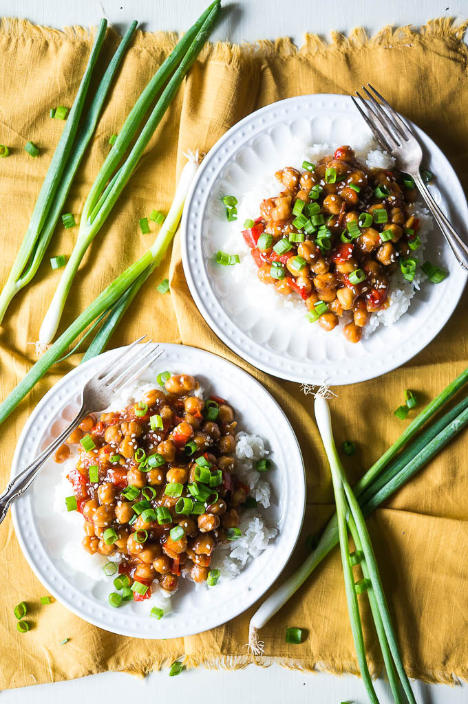 Chickpeas and white rice on a white plate with green onions on a yellow napkin.