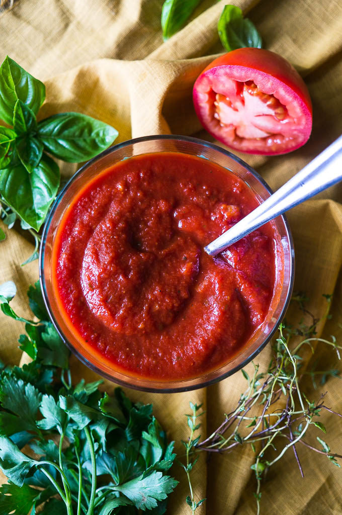 Pizza sauce on a yellow napkin with herbs and a tomato