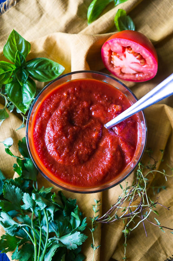 Pizza sauce on a yellow napkin with herbs and a tomato