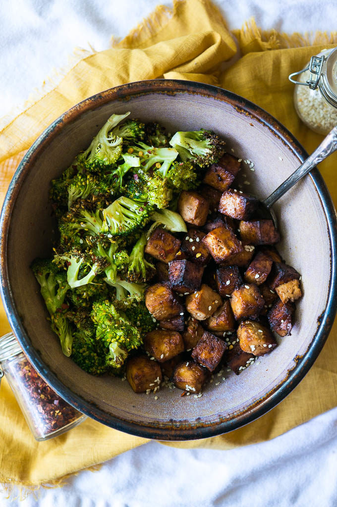 Crispy tofu and roasted broccoli in a pottery bowl