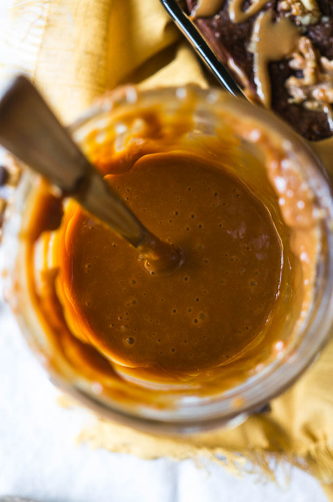 Caramel in a glass jar with a spoon on a yellow napkin